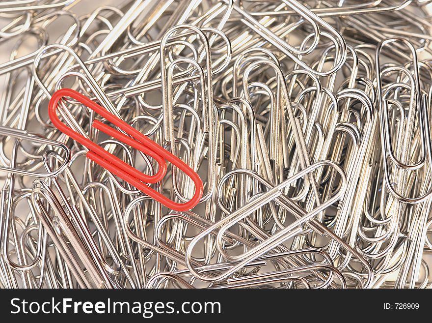 One red paper clip in a pile of silver ones has a special purpose for urgent messages. One red paper clip in a pile of silver ones has a special purpose for urgent messages.