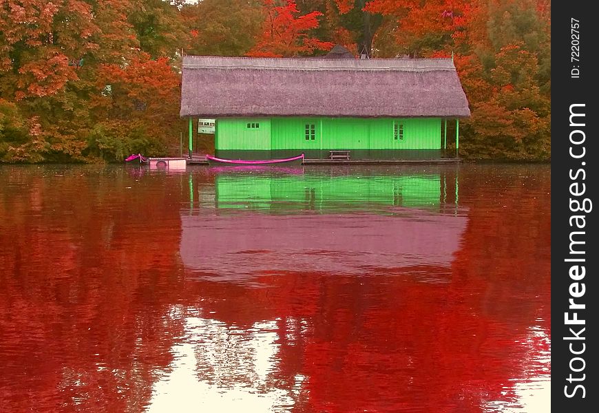 spooky interpretation with overfiltered view with green wooden house on the bloody lake in autumn season. spooky interpretation with overfiltered view with green wooden house on the bloody lake in autumn season