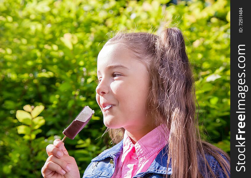 Smiling girl in a blue denim jacket eating ice cream outside closeup. Smiling girl in a blue denim jacket eating ice cream outside closeup