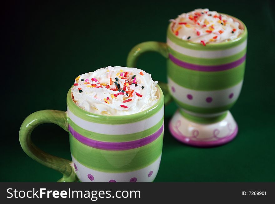 Colorful striped mugs of hot cocoa and whipped cream