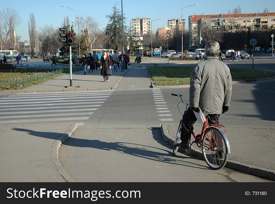 An old man riding a bicycle waits for the green light. An old man riding a bicycle waits for the green light