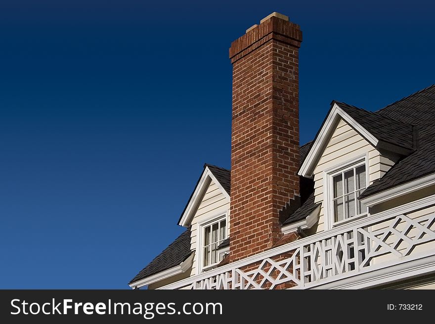 A brick chimney rises between two roof windows. A brick chimney rises between two roof windows.