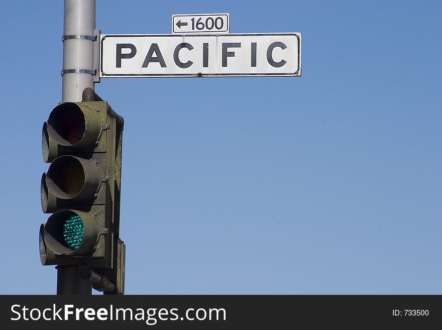 A street lamp with the green light on, with a �Pacific� road sign attached. A street lamp with the green light on, with a �Pacific� road sign attached.