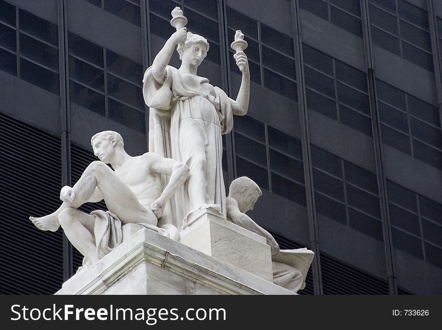 A statue of a Woman holding two flames on top of a neoclassical styled building. A statue of a Woman holding two flames on top of a neoclassical styled building.