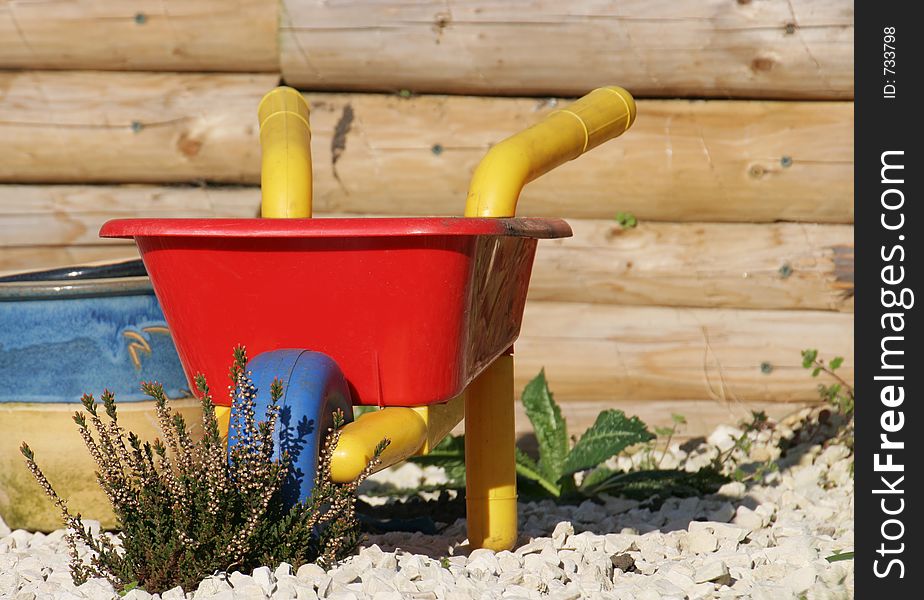 A childs wheel barrow outside in spring. A childs wheel barrow outside in spring