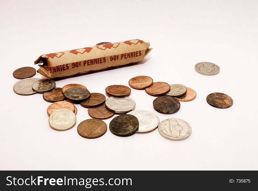 A roll of pennies sits among other American coins