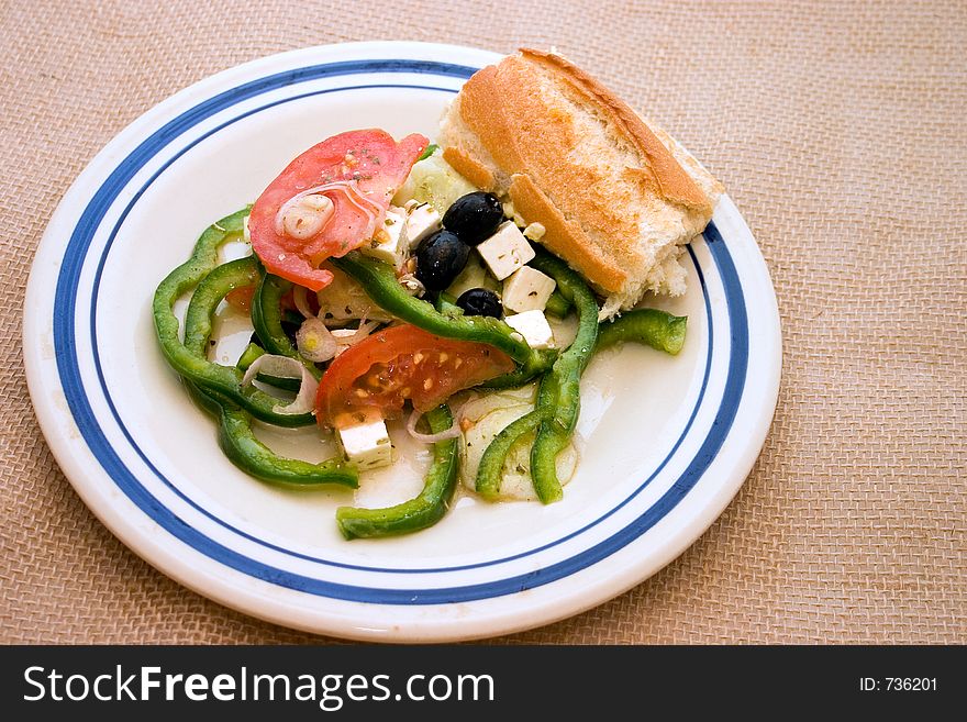 My version of a simple Greek salad with crusty french bread on old crockery plate. Horiatiki means village. My version of a simple Greek salad with crusty french bread on old crockery plate. Horiatiki means village.