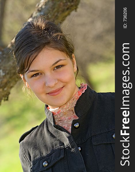 Young woman sitting beneath a tree smiling. Young woman sitting beneath a tree smiling