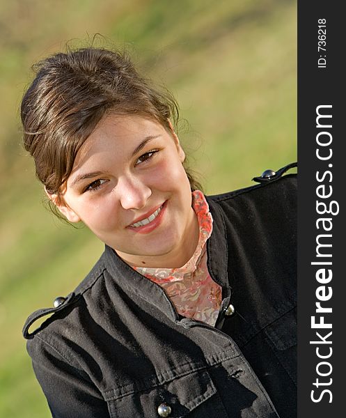 Young woman sitting beneath a tree smiling. Young woman sitting beneath a tree smiling