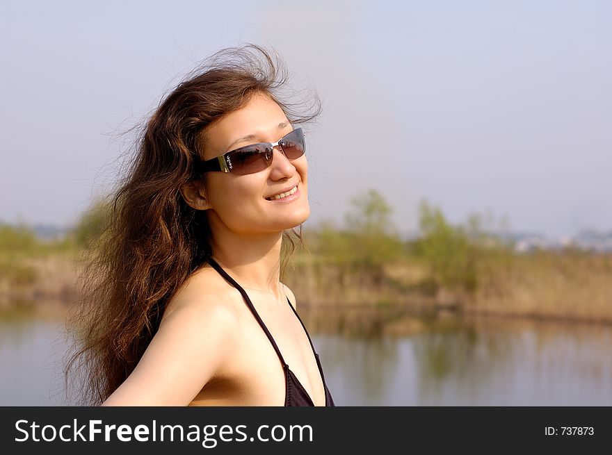 Happy young woman standing near a lake in the nature smiling. Happy young woman standing near a lake in the nature smiling