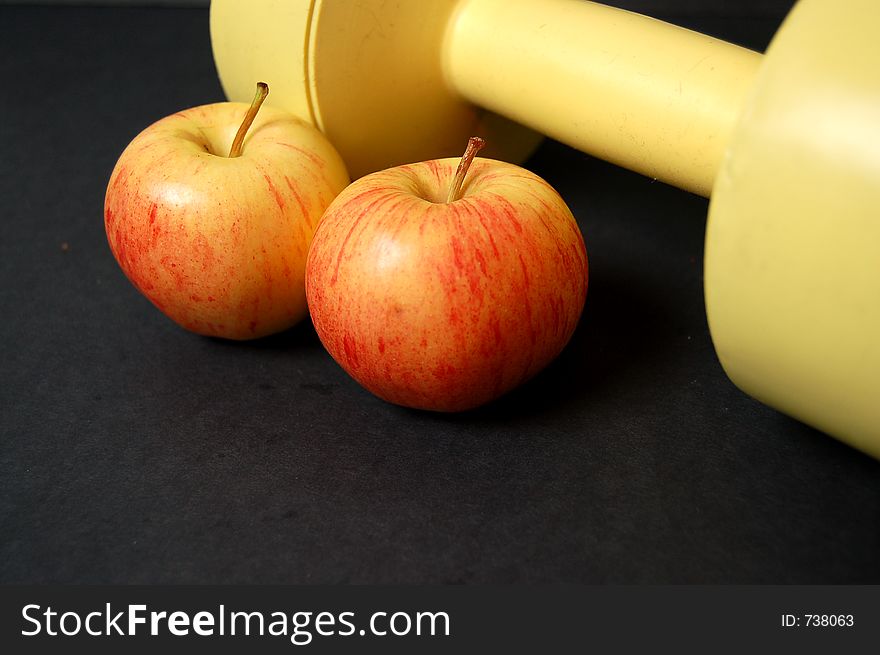 This is an image of a two apples and a yellow dumbbell. (Please let me know where the image will be used by leaving a message in the Comments Section/See Portfolio). This is an image of a two apples and a yellow dumbbell. (Please let me know where the image will be used by leaving a message in the Comments Section/See Portfolio)