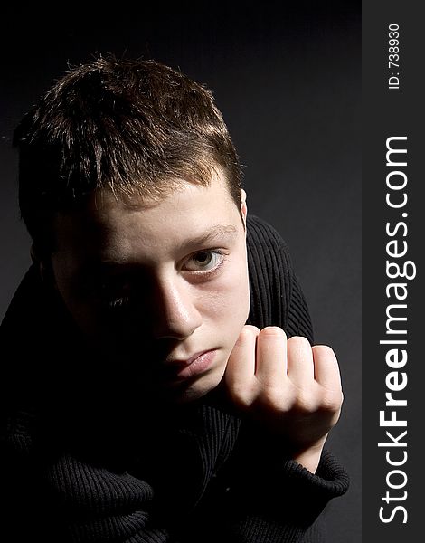 Teenager portrait looking up towards camera against black backdrop