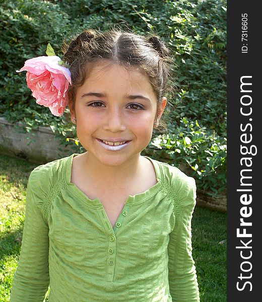 Cute little girl playing dress up with a flower in her hair and lipstick on