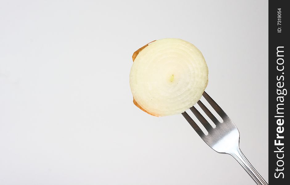 A sliced white onion pierced on the end of a dinner fork. A sliced white onion pierced on the end of a dinner fork.