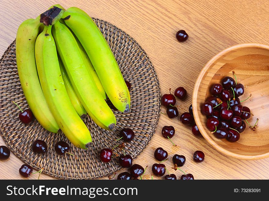 A Wooden Bowl of Fruits on a Wooden Background, Banana, Cherries, Peaches