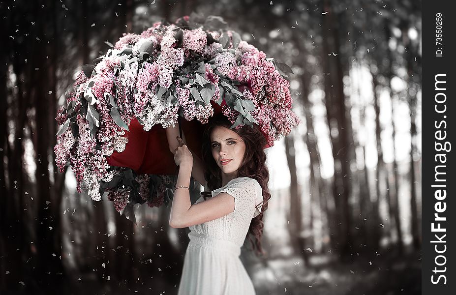 Teen girl standing under an umbrella of lilacs in the garden.