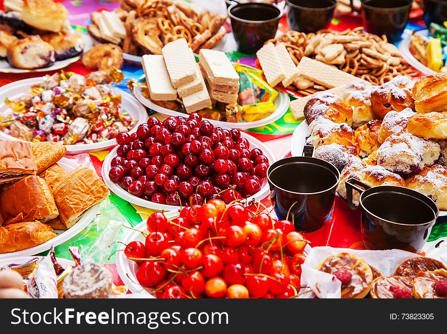 Festive table with sweets, chocolates, waffles, cherries outside on summer day. Festive table with sweets, chocolates, waffles, cherries outside on summer day