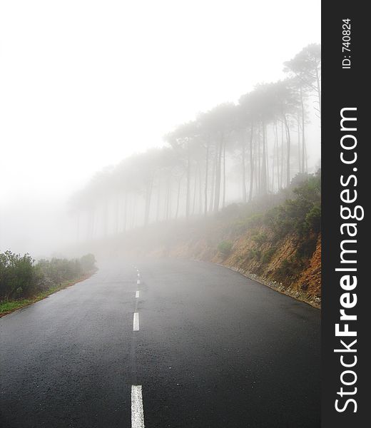 Portrait photo of a mountain slope shrouded in mist with road. Portrait photo of a mountain slope shrouded in mist with road.