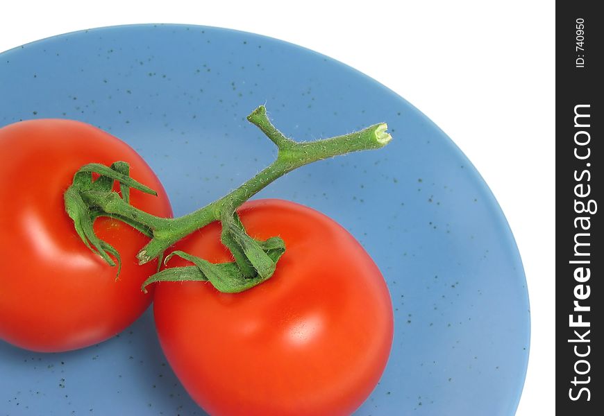 Two red tomatoes on a blue plate on white background