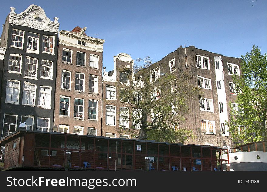 Building reflections from beautiful Amsterdam on a clear water early in the morning. Building reflections from beautiful Amsterdam on a clear water early in the morning