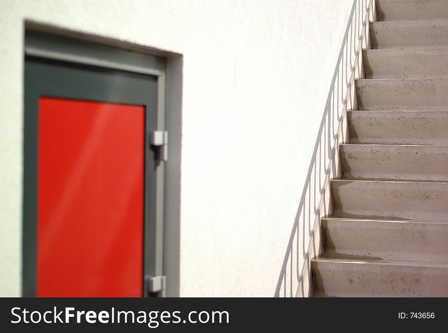 Concrete stairs next to a red door. Concrete stairs next to a red door.