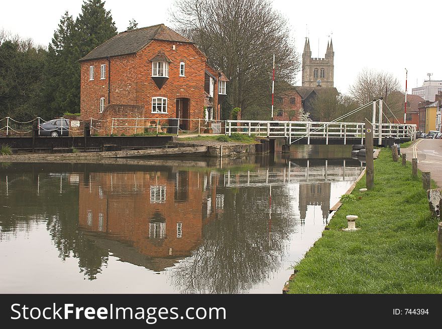 Red bricked house next to canal with church in background