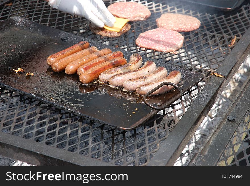 Hot dogs, sausage, and hamburger on an open grill. Hot dogs, sausage, and hamburger on an open grill.