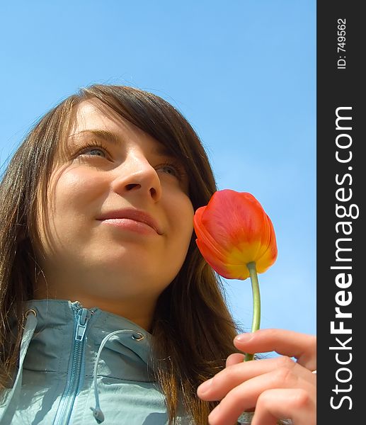 The girl with a tulip on a background of the sky. The girl with a tulip on a background of the sky