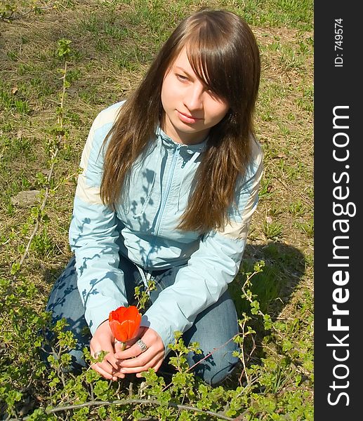 The girl with a tulip on a background of a grass. The girl with a tulip on a background of a grass