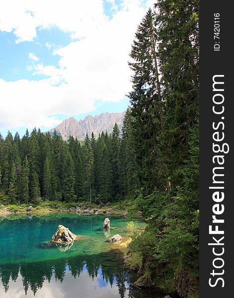 Green pines woods, blue turqoise Carezza  lake & view on Sella montain group, Italy. Green pines woods, blue turqoise Carezza  lake & view on Sella montain group, Italy