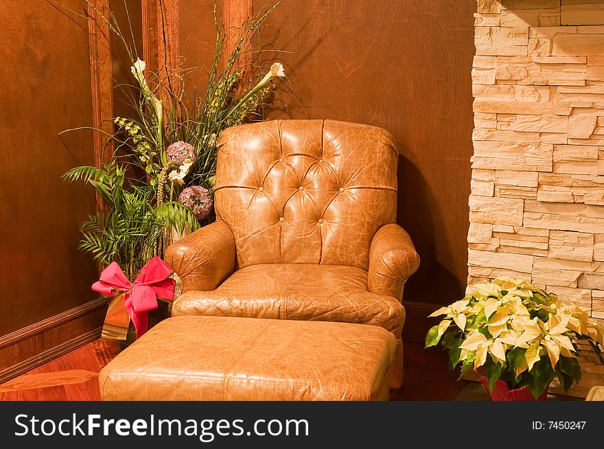 A view of a comfortable, stuffed leather chair next to a decorative green plant in a living room corner. A view of a comfortable, stuffed leather chair next to a decorative green plant in a living room corner.