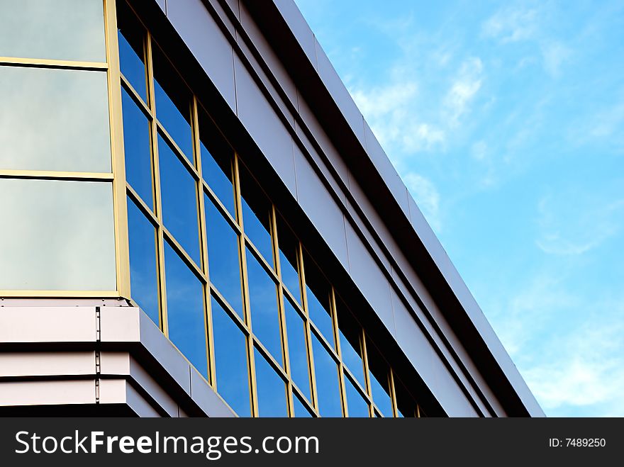 Corporate building with glass windows on cloudy sky background