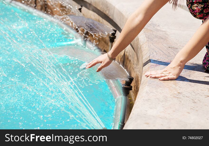 Girl put her hand in a fountain hands closeup