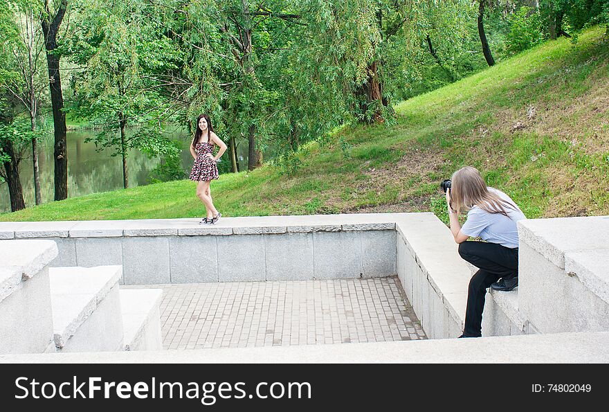 Photographer takes a women standing on the stairs in the park on summer day. Photographer takes a women standing on the stairs in the park on summer day