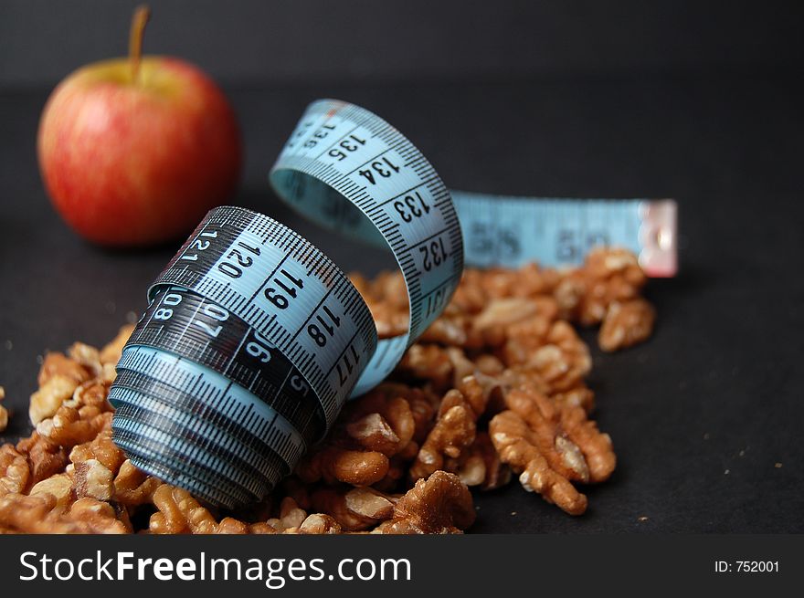 This is an image of a measuring tape, walnuts and an apple. (Please let me know where the image will be used by leaving a message in the Comments Section/See Portfolio). This is an image of a measuring tape, walnuts and an apple. (Please let me know where the image will be used by leaving a message in the Comments Section/See Portfolio)