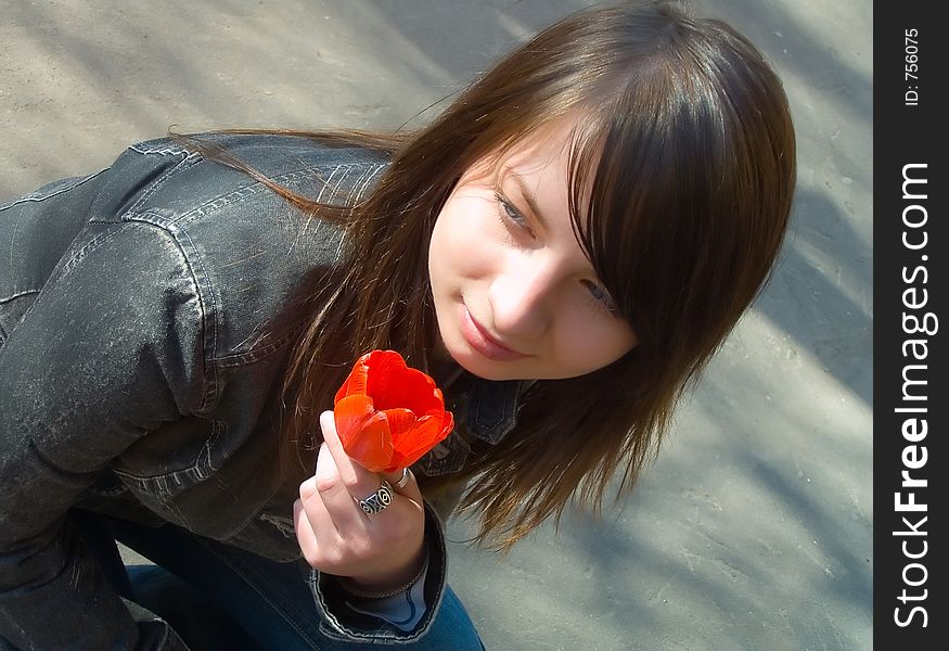 The girl with a flower on a background of asphalt. The girl with a flower on a background of asphalt