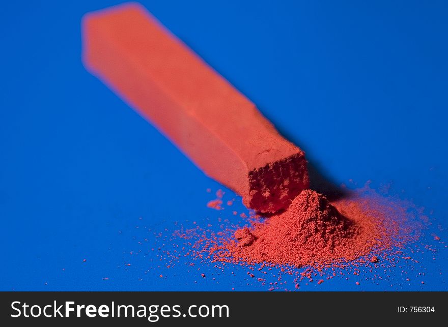 Red pastel with fine heap on blue background (shallow DOF)