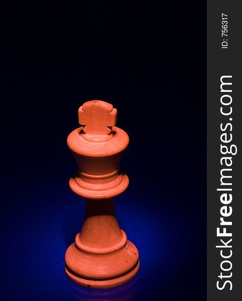 King chess piece with red light from above on blue background. King chess piece with red light from above on blue background