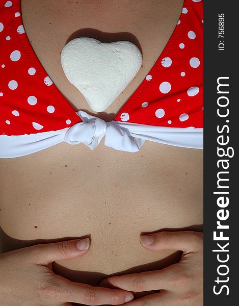 A white stone heart between breasts. A white stone heart between breasts