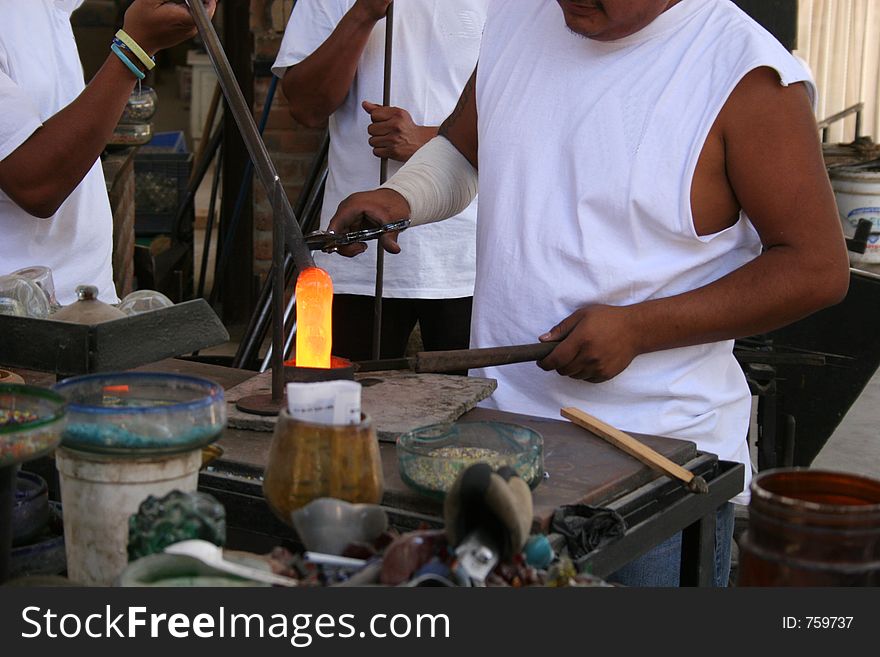 Glass blower working molten glass