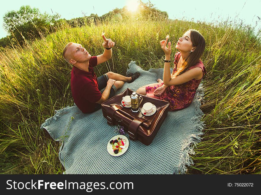 Guy with a girl in summer on the grass drinking tea