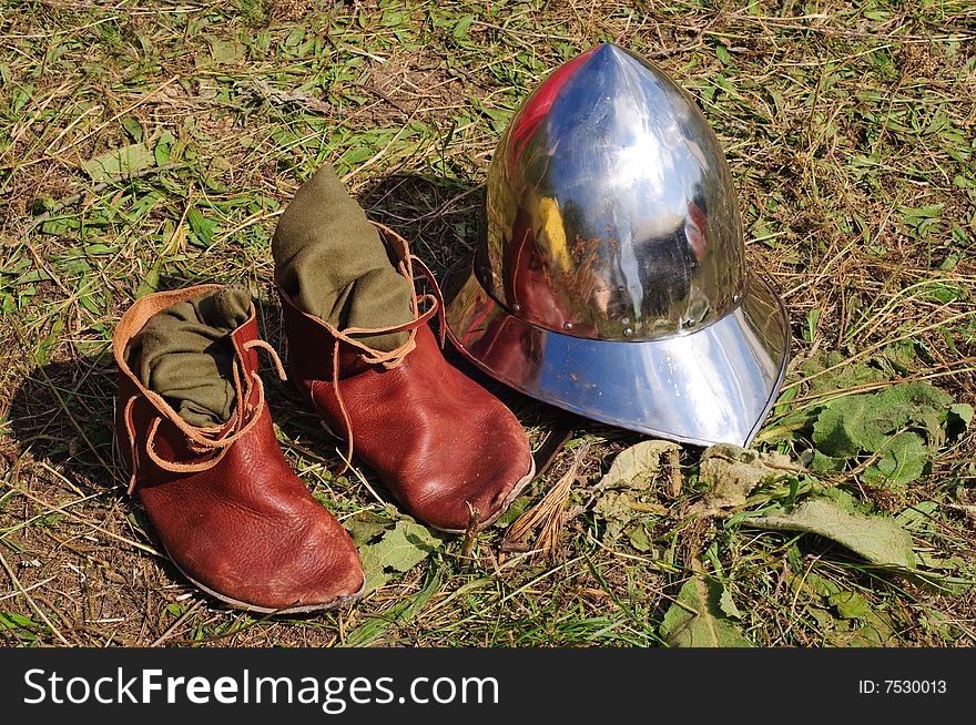 Teutonic medieval boots and helmet lying on the ground