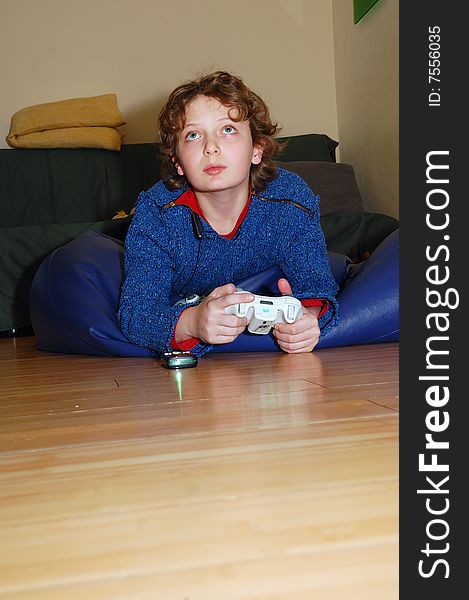 Blond boy lying on the floor and playing his vidoe game. Blond boy lying on the floor and playing his vidoe game