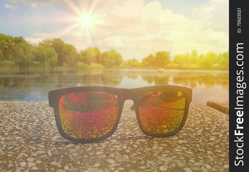 Picture with fashionable colorful sunglases in a sunny day of summer and beautiful landscape on the lake