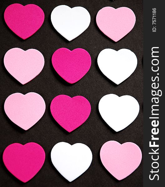 Pink and white valentine hearts on black background