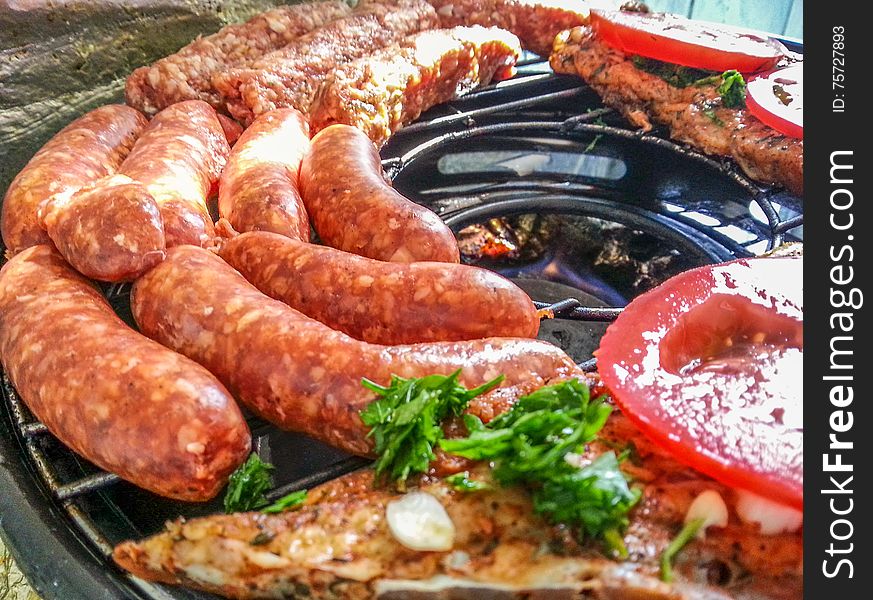 Picture with traditional romanian food with grilled sausages and barbeque ,sheep,mititei and tomatoes before cooking. Picture with traditional romanian food with grilled sausages and barbeque ,sheep,mititei and tomatoes before cooking