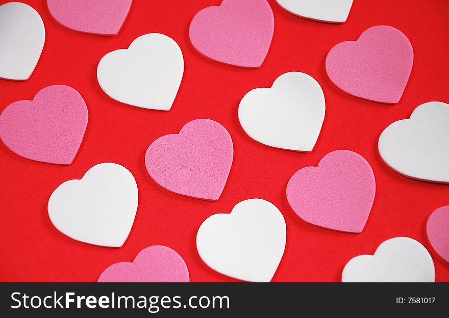 Pink and white valentine hearts on red background