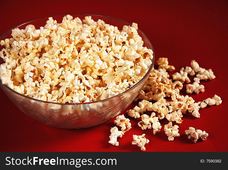 Fluffy popcorn in bowl against red background