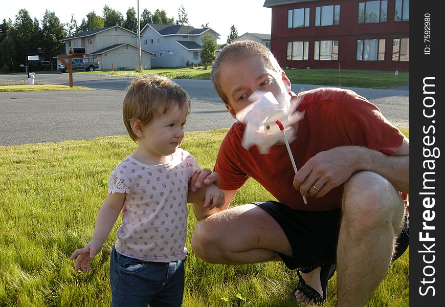 Daughter and daddy playing with a pinwheel. Daughter and daddy playing with a pinwheel