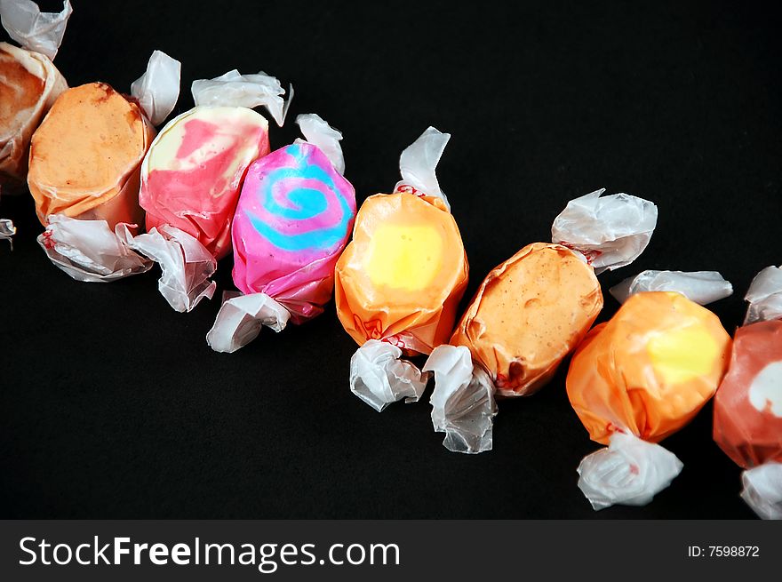 Colorful wrapped taffy candy on black background